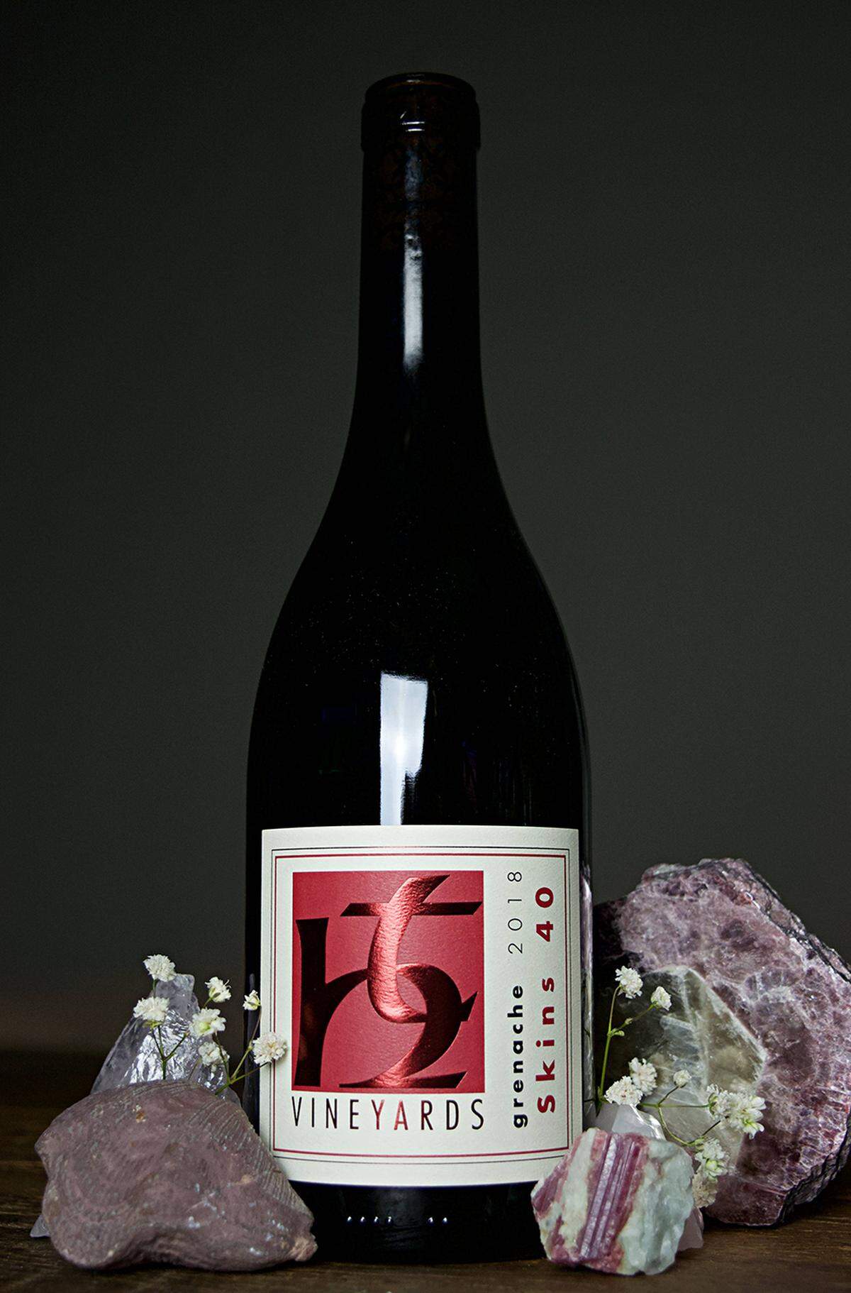A wine from TH Estate Wines, surrounded by crystals and flowers.