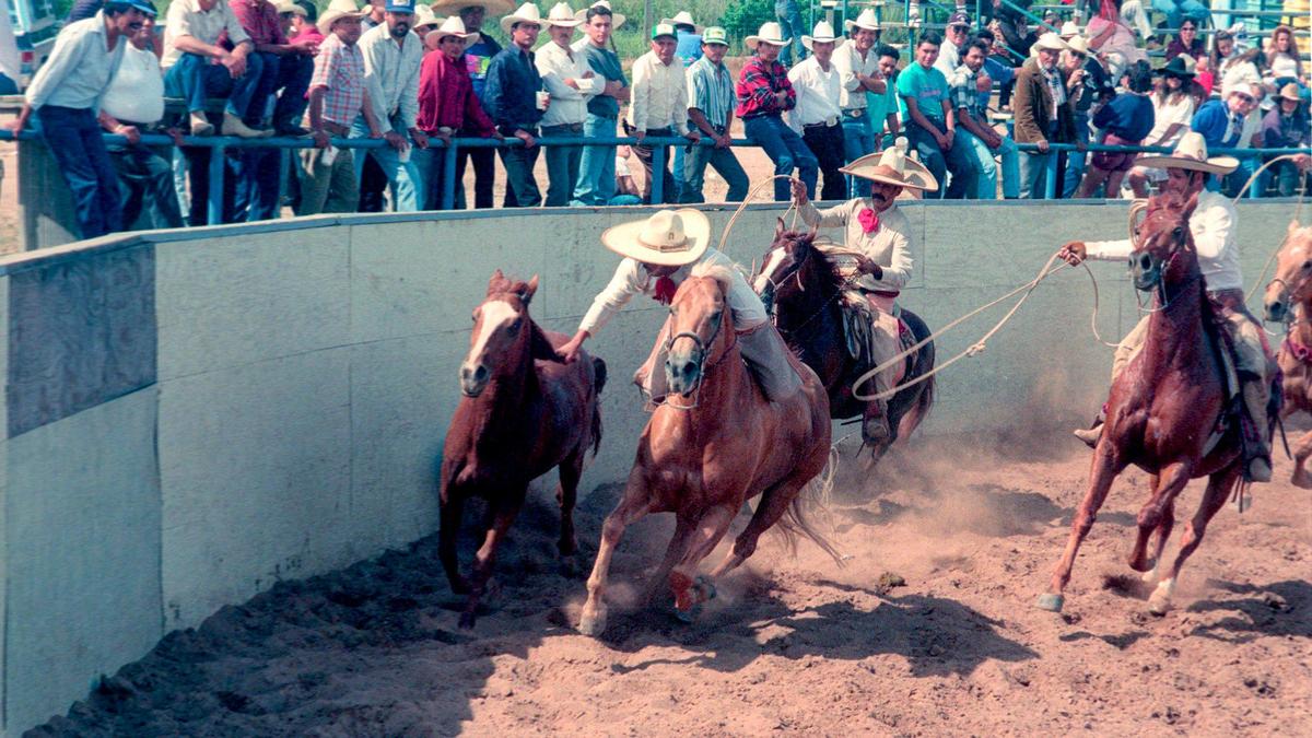 In an event called “paso de muerte” — or “pass of death” — charro Jose Crespo rides his horse at full speed alongside a wild horse then jumps onto the wild horse as his team follows. A charreada, or Mexican rodeo, was held at Nipomo Regional Park on May 30, 1993.