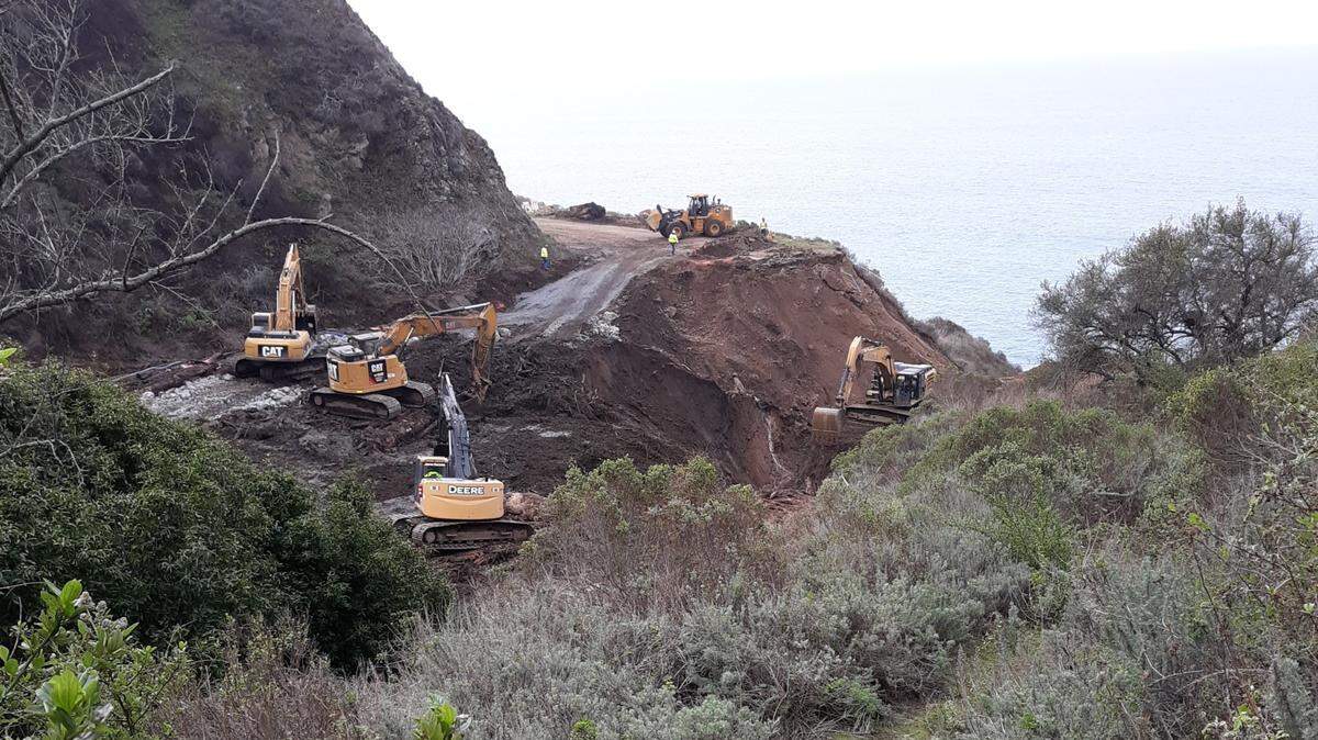 Excavator drivers work to clear woody debris and mud from the Rat Creek canyon crevasse in the Highway 1 pavement, about 30 miles north of the line between San Luis Obispo and Monterey counties. Drivers cannot go all the way from Cambria to Carmel until repairs are made; there’s no estimate yet about how long that will take.