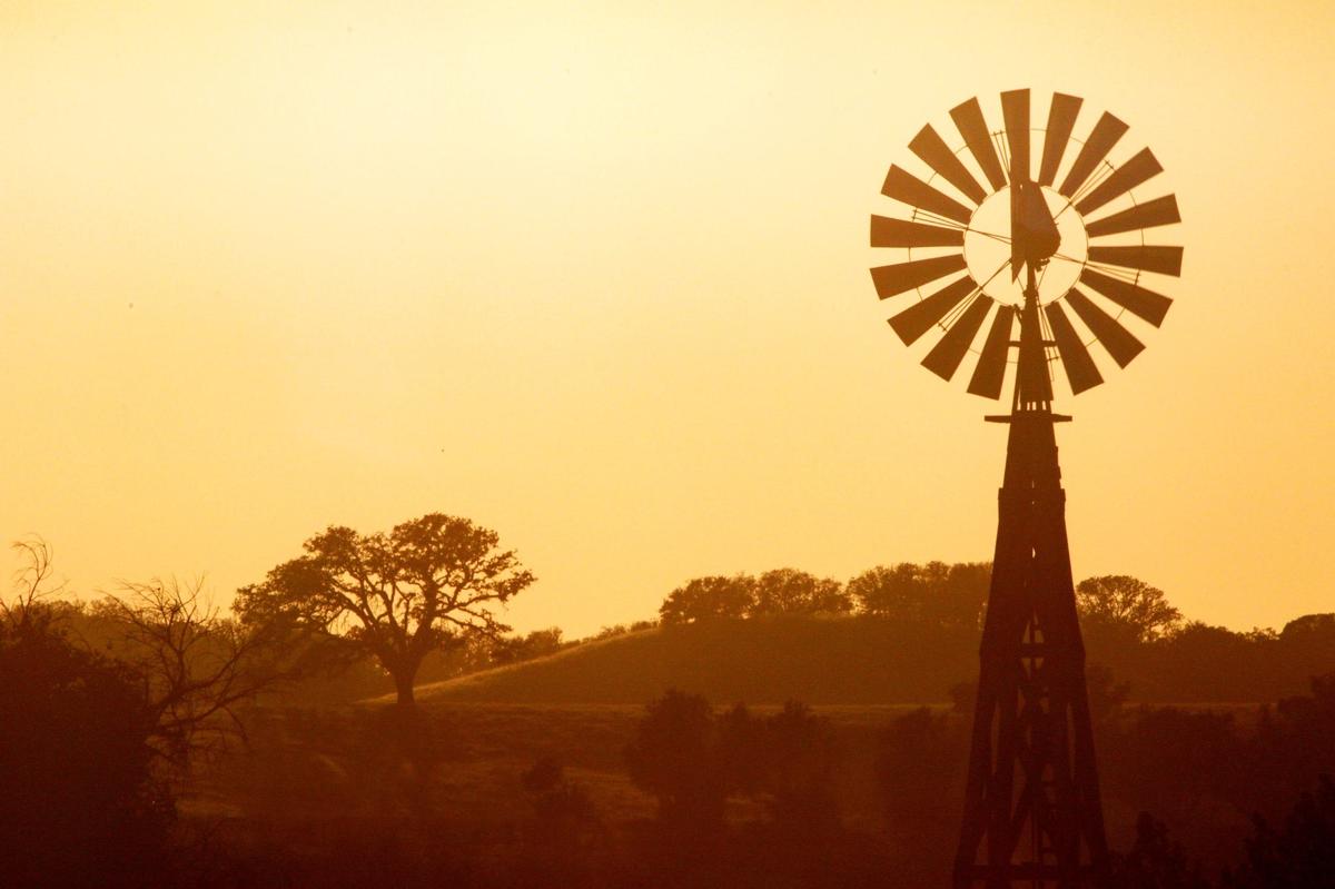 The sky turns orange behind a windmill and oaks near Creston shortly before sunset along Highway 41 on June 23, 2016.