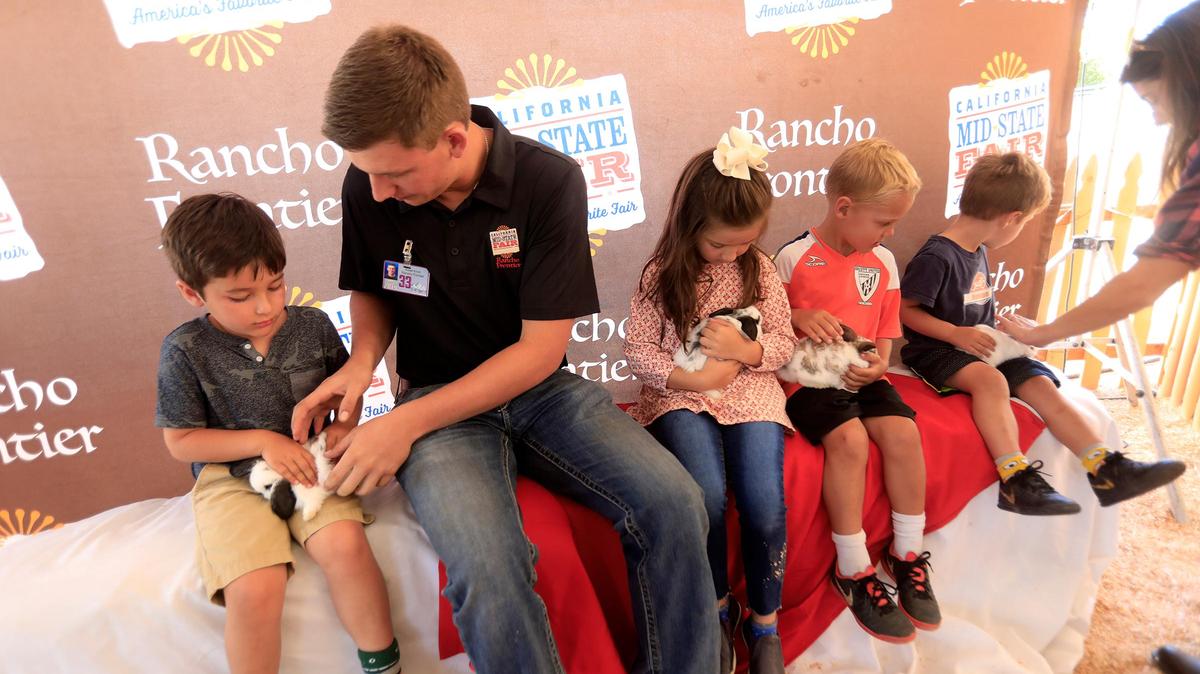 Robby Knoch, volunteer with Rancho Frontier, helps kids gently hold some small rabbits at the California Mid-State Fair in Paso Robles in 2019. The fair will postpone its 2021 Youth Rabbit Show due to state concerns of a Rabbit Hemorrhagic Disease outbreak.