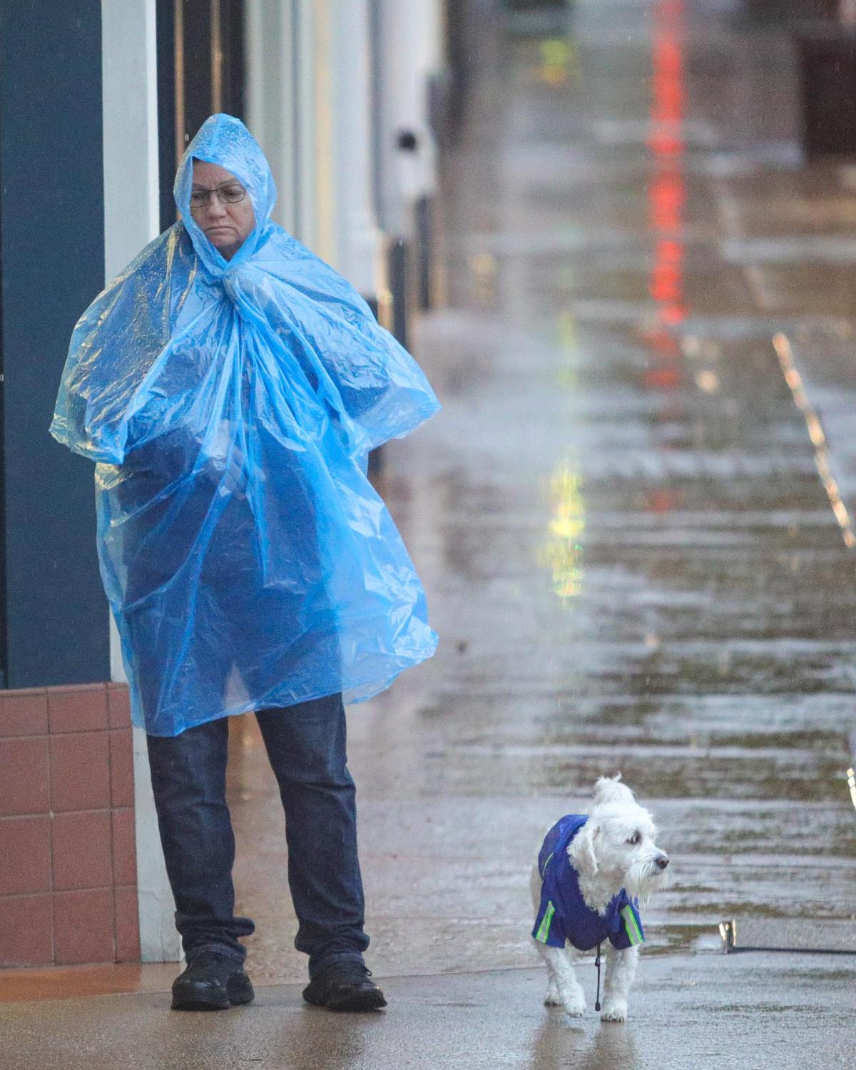 Jean St. James and Marshmallow wait for the light to change at Chorro Street as rain continued to fall in downtown San Luis Obispo on Tuesday, Dec. 14, 2021.