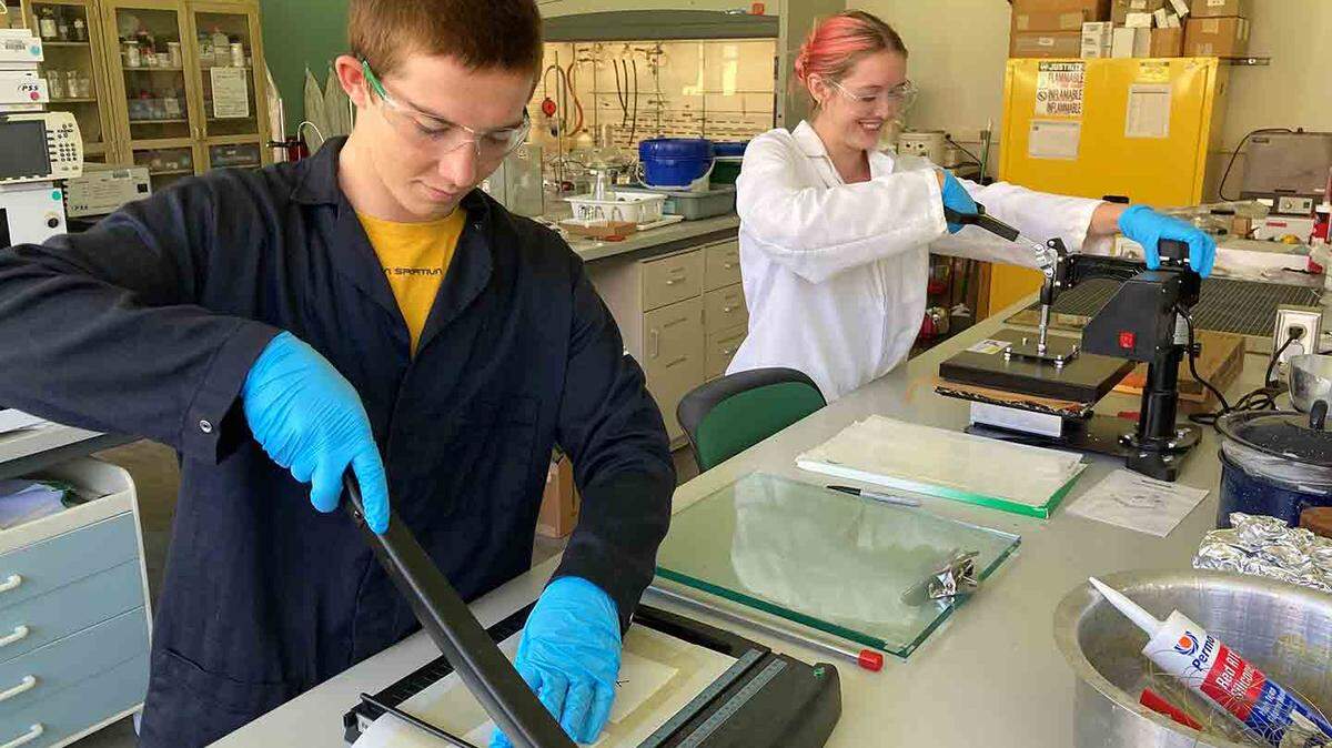 Cal Poly students Reed Kellar, a construction management major, and Taylor Vaughan, a biochemistry major, work in Cal Poly Chemistry Professor Phil Costanzo’s research lab. Reed is cutting adhesive coupons, and Taylor is bonding fabrics.