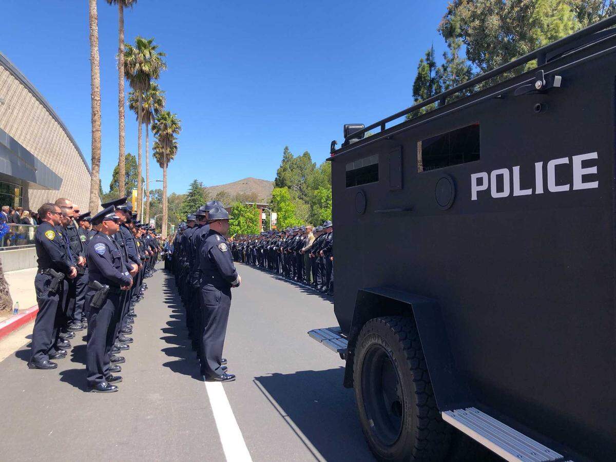 Police officers wait to deliver the body of Det. Luca Benedetti into an armored car ahead of his funeral procession.