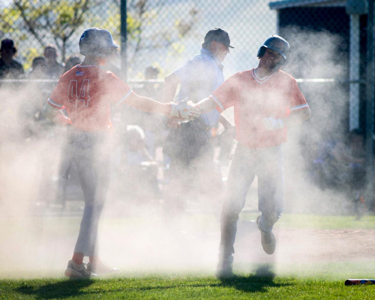 Damon Mitchell, left, shakes hands in a cloud of dust kicked up by Drew Cappel who scored in a slide home. Atascadero won 8-3 over San Luis Obispo in a baseball game May 3, 2024.