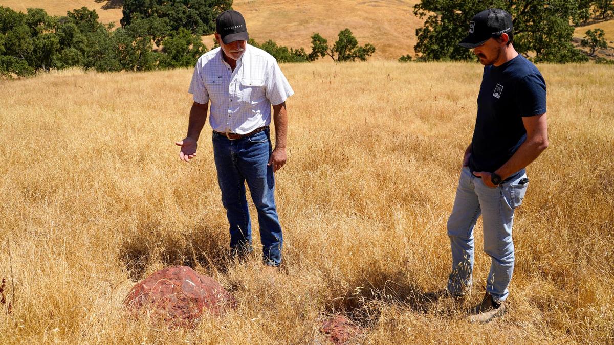 Adelaide Springs Ranch owner Laird Foshay, left, and Land Conservancy conservation program manager Cain Silvey check out cinnabar rocks on the property on July 15, 2025.