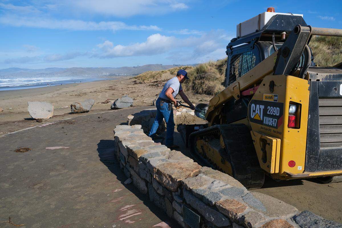 A parking lot repair crew member shovels dirt in the main parking lot of Morro Rock in Morro Bay on Jan. 3, 2024.