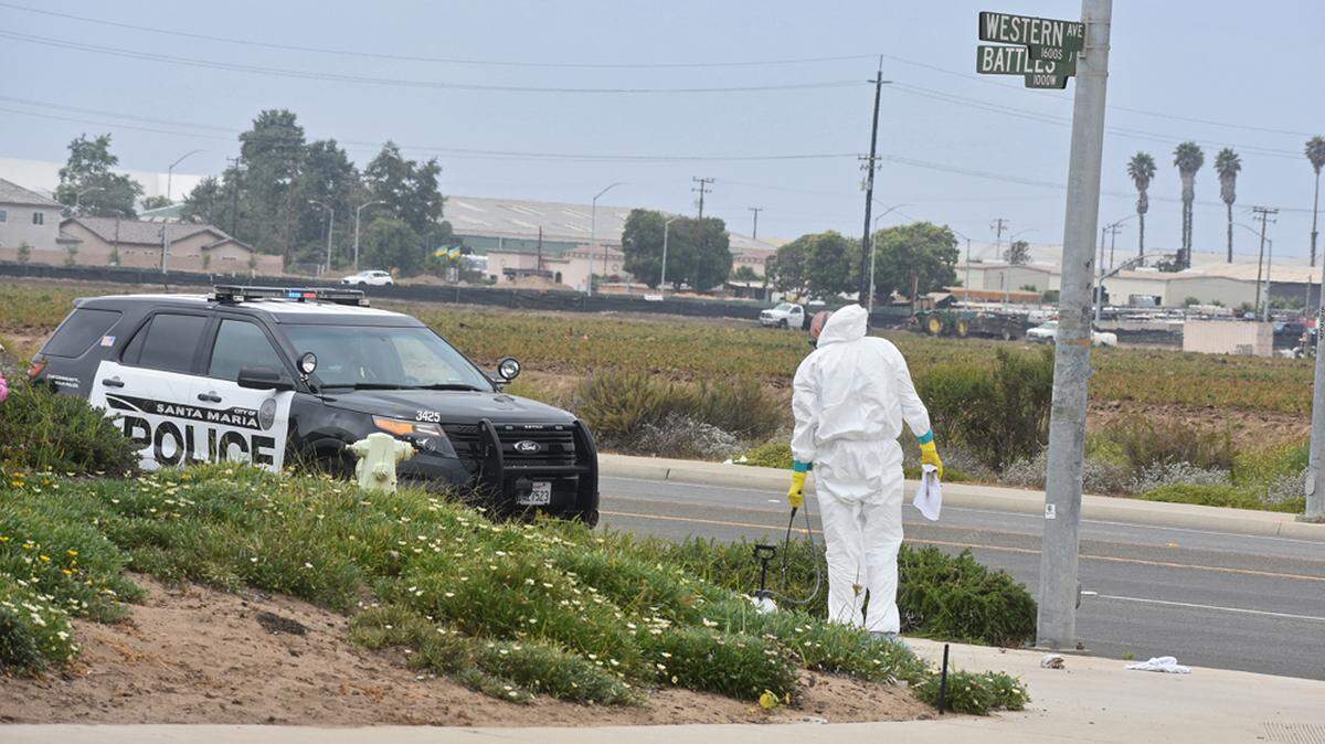 A worker cleans the sidewalk where a man was shot multiple times Tuesday morning on the corner of Battles Road and Western Avenue in Santa Maria, California.