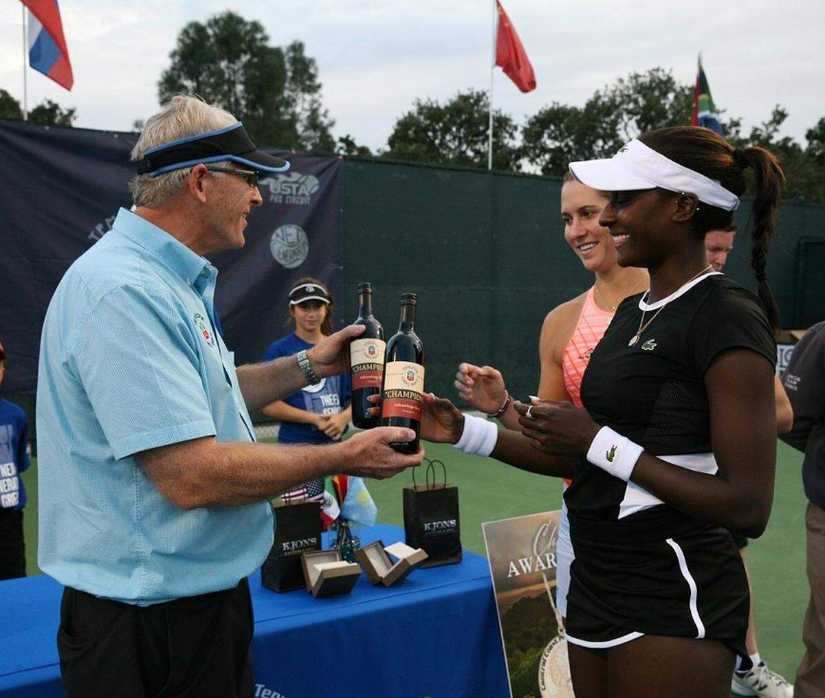 Templeton Tennis Ranch owner Ralph Goehring presents Asia Muhammad and her doubles partner Maria Sanchez with wine following their tournament victory last year.