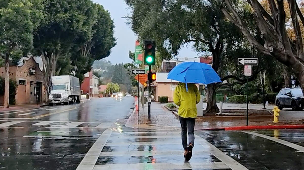 A man with an umbrella crosses Higuera Street as light rain hit San Luis Obispo on Thursday, Dec. 12, 2024.