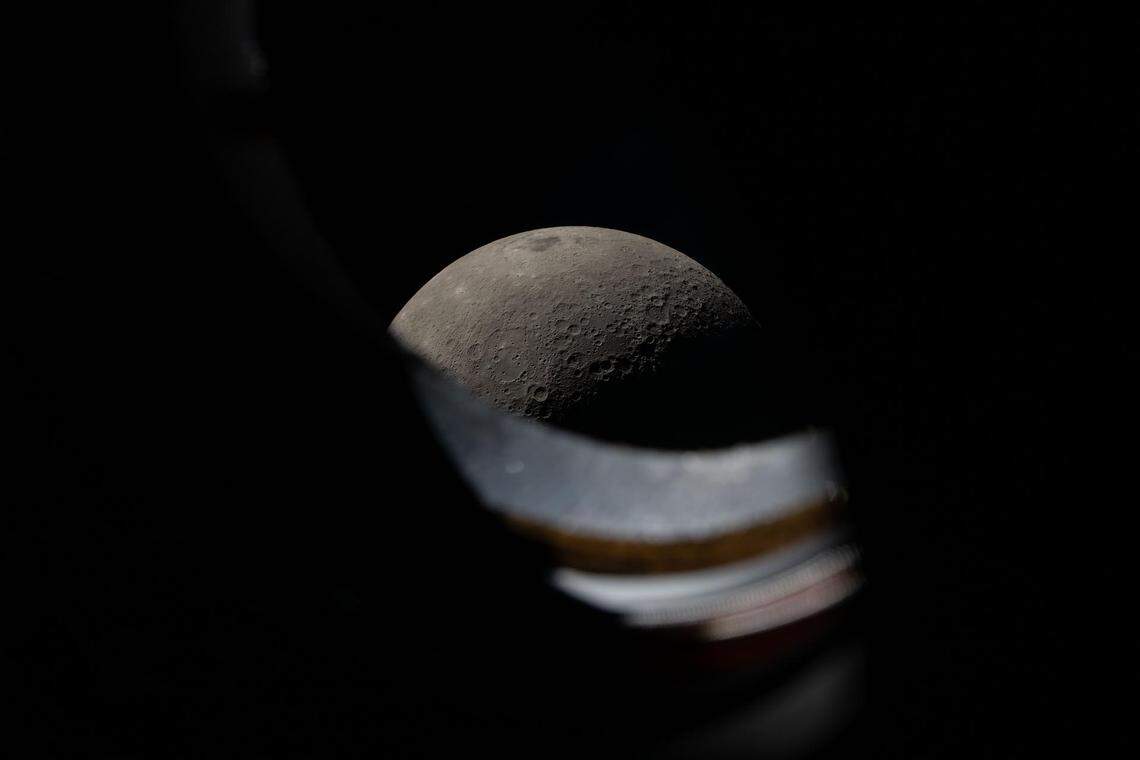 The moon peeks above the window sill of the Orion spacecraft during the Artemis II lunar flyby on April 6, 2026. The Artemis II crew spent about seven hours at the Orion windows during the flyby, taking photos and recording observations on the moon to share with scientists on the ground.