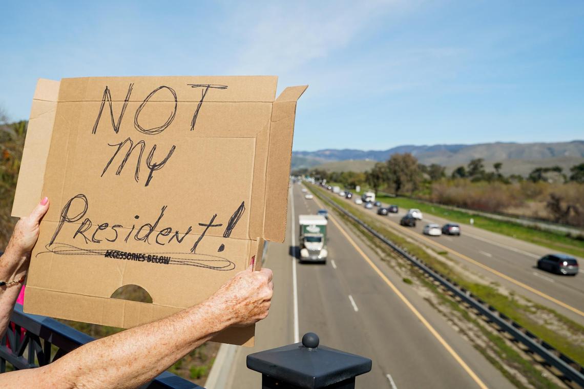 Protesters hold signs and chant to show their opposition to the policies of Donald Trump’s second term in office and Elon Musk’s Department of Governmental Efficiency, on Los Osos Valley Road on Monday, Feb. 17, 2025.