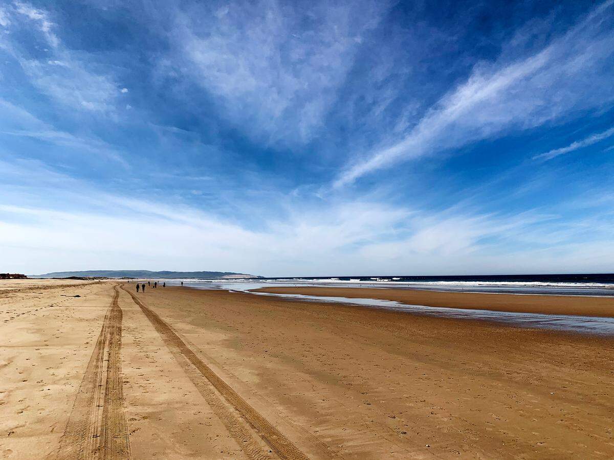 Beachgoers walk along the water’s edge at Oceano Dunes State Vehicular Recreation Area, which has been temporarily closed to vehicles.