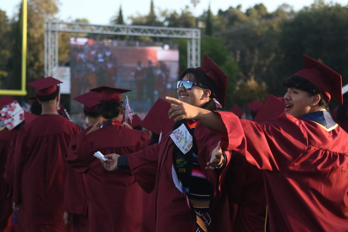 Paso Robles High School seniors gesture to their family and friends standing on the sidelines of War Memorial Stadium during commencement on June 5, 2026. The ceremony celebrated around 414 graduates.