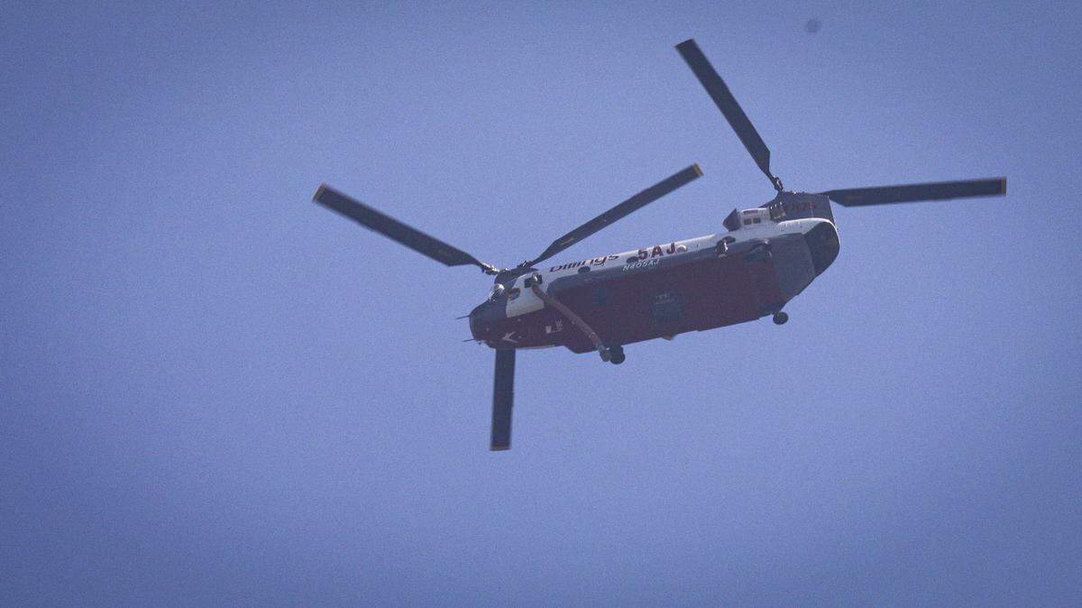 A firefighting helicopter flies near Lopez Lake on Aug. 8, 2025. As of the morning of the eighth day of the Gifford Fire, 3,431 firefighters were working in shifts on the 99,232-acre blaze.