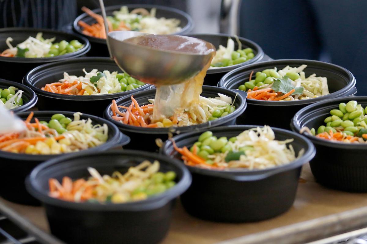A food service worker pours warm broth over ramen and fresh vegetables at Flamson Junior High School in Paso Robles, where students enjoy from-scratch meals made with fresh ingredients from local farms and ranches.