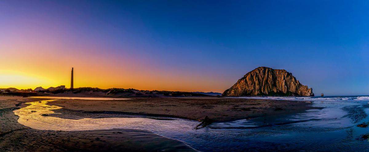 The sunrise illuminates Morro Rock and the stacks at the old power plant on a morning in Morro Bay.