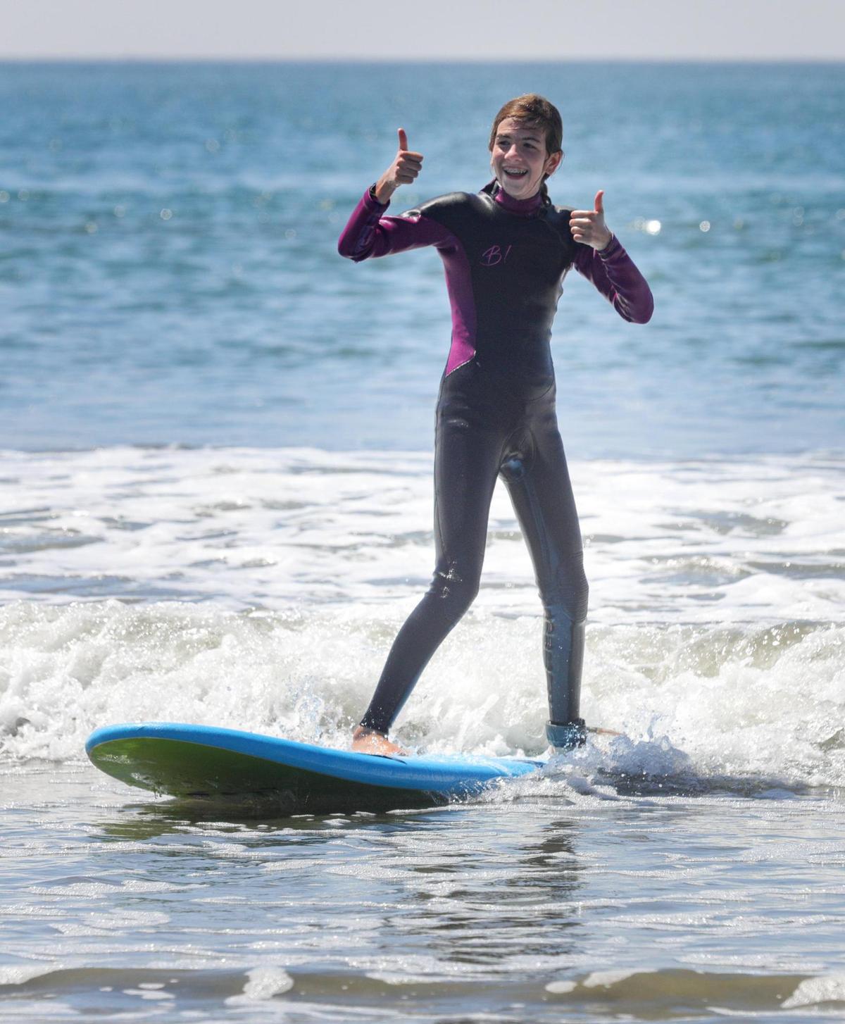 Sabine Bartlett, 11, gives thumbs up after completing a run on her surfboard. She and her brother were taking lessons from Anhase Martin, surf instructor with Good Clean Fun. Families enjoyed the cool weather at Cayucos as a heat wave was forecast for the upcoming days.