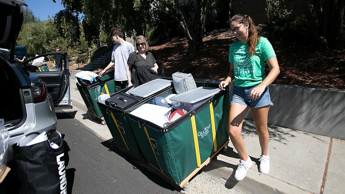 Cal Poly student Amalia Arndt helps Cindy Priscaro and Michael Priscaro, a marketing major, move the familiar green bins filled with Priscaro’s belongings into the dorms on Tuesday, Sept. 13, 2022, as the university’s new freshman class arrives on campus. The loading zone began at Grand Avenue and snaked around to the top level of the parking structure at the Performing Arts Center. After the new students move in, they’ll join their WOW groups on Wednesday evening for four days of orientation before classes begin next week.