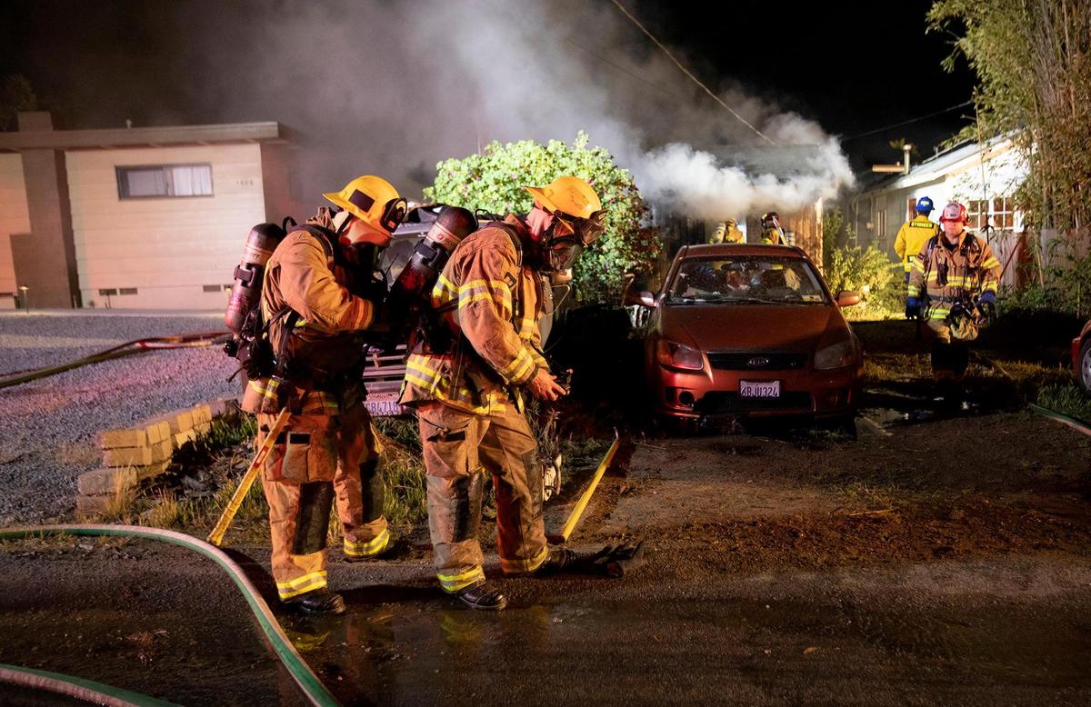 Cal Fire firefighters suit up with oxygen tanks prior to entering the building. Cal Fire crews are responded to reports of a fully-engaged house fire on 7th Street in Los Osos.