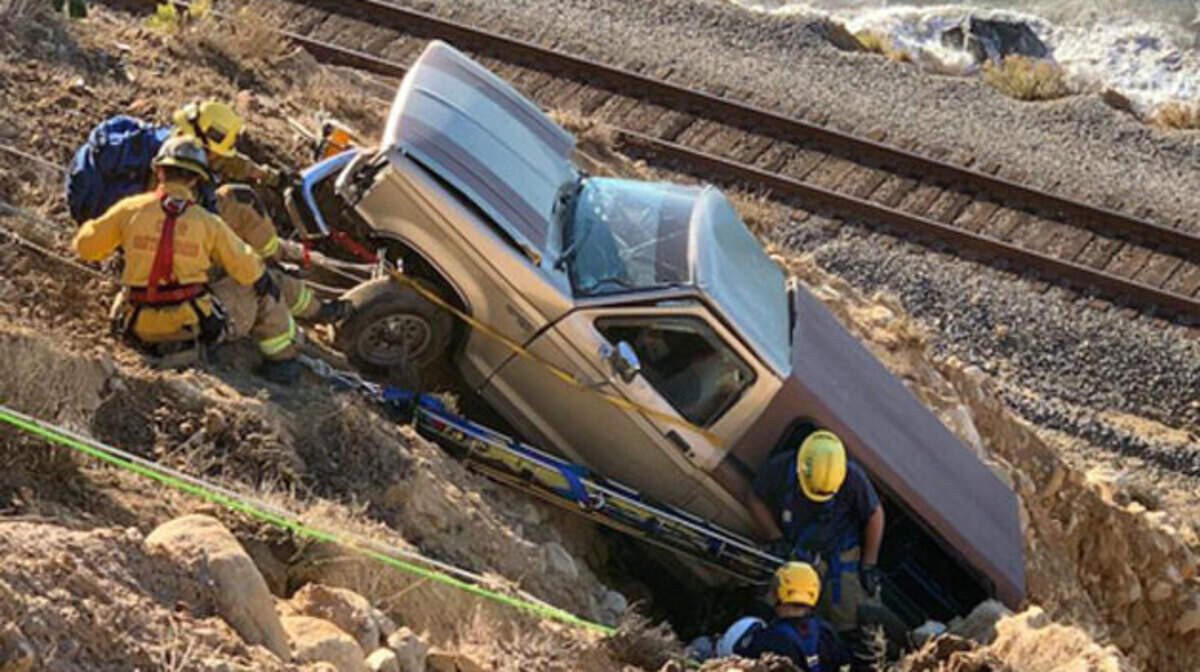 Firefighters work to rescue the driver of a pickup truck that veered off Highway 101 near Summerland on Monday and plunged down the steep cliff.