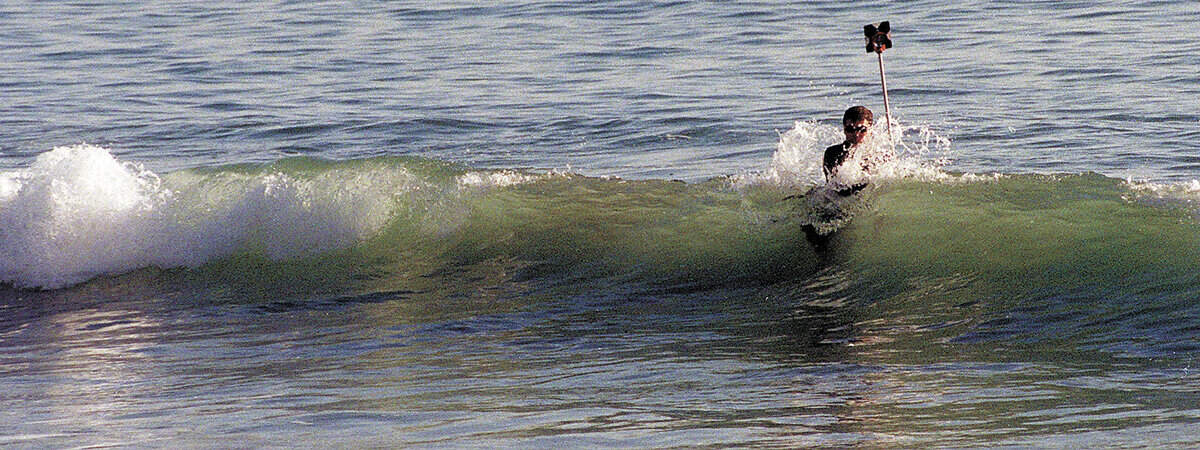 Rick Foss, a surveyor with Cannon Associates, had to put on a wetsuit to take measurements at Avila Beach in January 1999. They were measuring the movement of beach sand for studies connected to the work Unocal was doing to clean up oil contamination. Photo by David Middlecamp