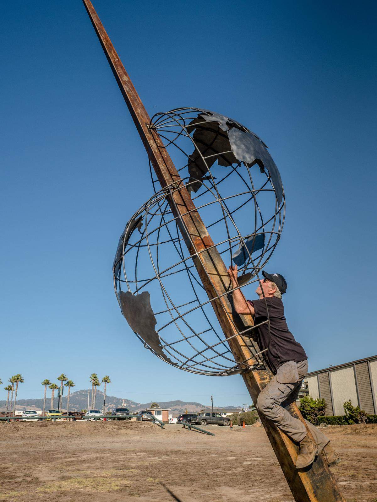 Metalworker Rob Foster of Atascadero shinnies up the angled support to secure a divided image of the earth on a sculpture installed Oct. 1, 2021, near the San Simeon shoreline. The people who created the nearly three-story-tall monument, titled “Shift,” want to highlight the many divisions inthe world and make people think about what they can do to help bring the world and its inhabitants back into harmony.