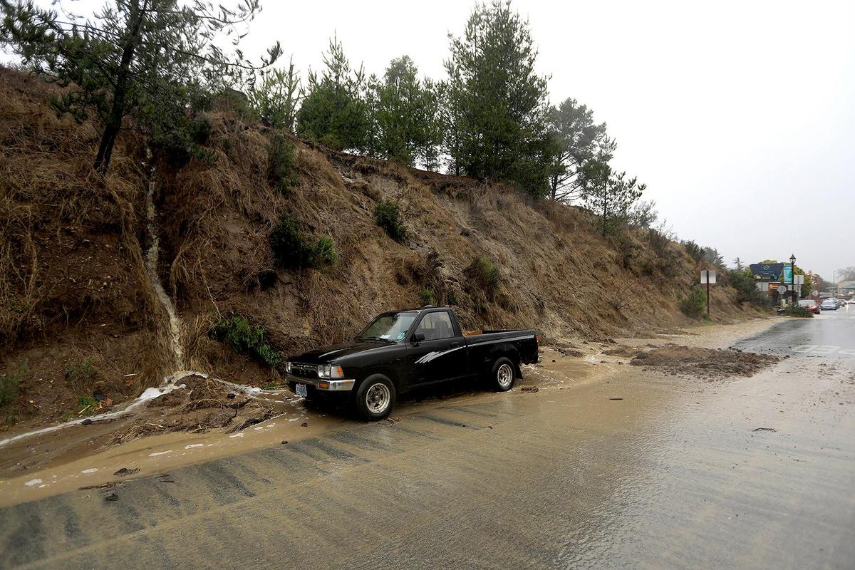 Water and mud flows from a small hillside onto Main Street at Burton Drive in Cambria. A strong storm hit the North Coast area with heavy rain and high winds on Jan. 27, 2021.