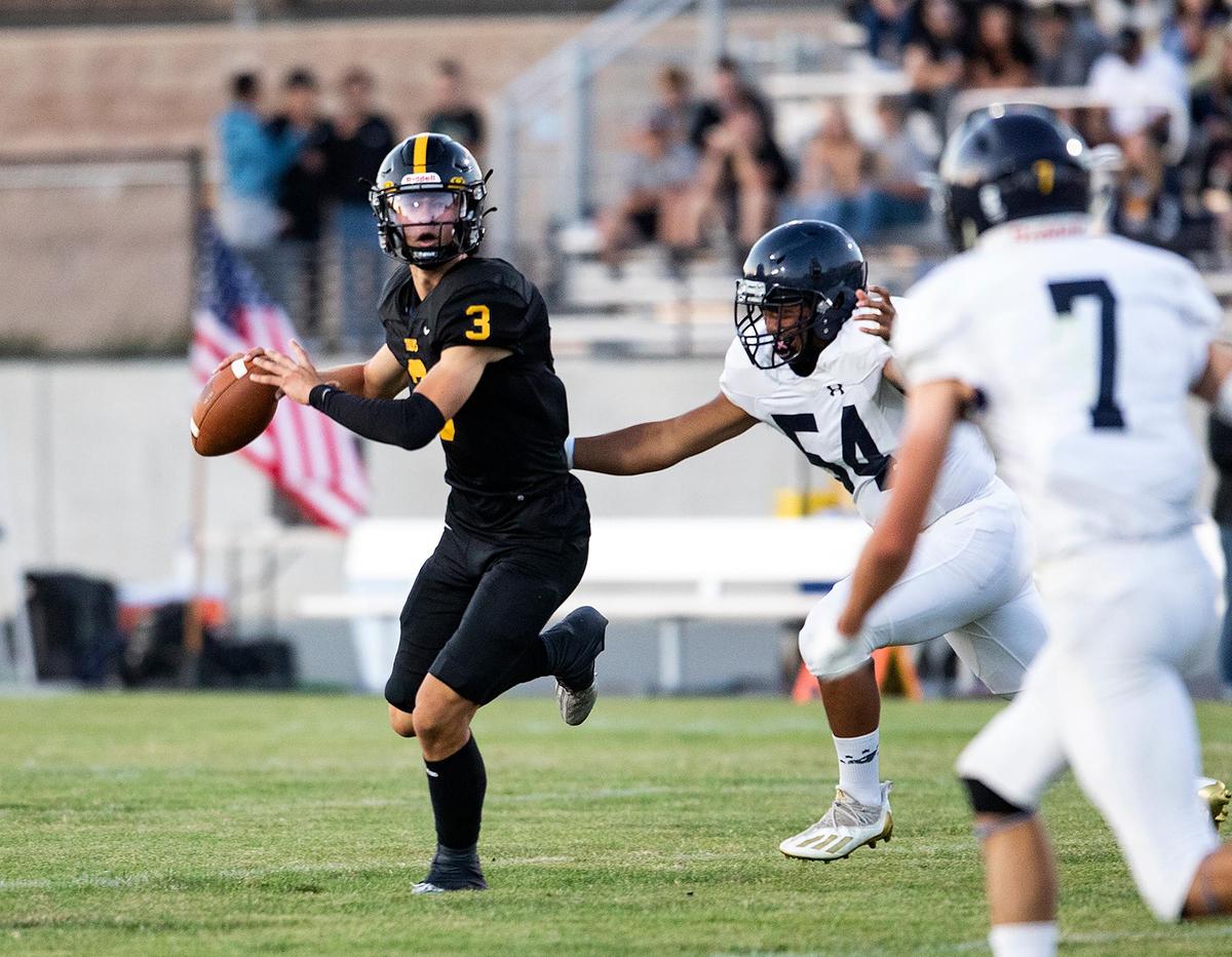 San Luis Obispo quarterback Jace Gomes rolls out for a pass with Arroyo Grande’s Moses Diaz in pursuit as the Eagles beat the Tigers 26-14 on Friday, Sept. 2, 2022.