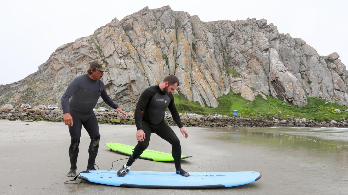 Kyle Kelly, a veteran who lost his lower right leg to a roadside bomb in Iraq, tests a new prosthetic limb with improved ankle flexibility designed by Cal Poly students. Van Curaza, founder of Operation Surf, left, assists.
