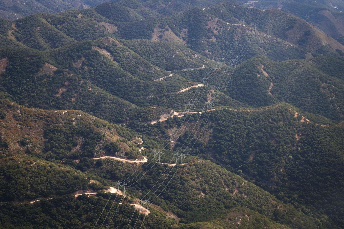 Dual sets of high tension power lines stretch inland from the Diablo Canyon nuclear power plant. The Northern Chumash Tribal Council organized an aerial tour of lands bordering the Chumash Heritage National Marine Sanctuary on Sept. 18, 2024. The flight was sponsored by EcoFlight, a nonprofit dedicated to appreciation of the environment.