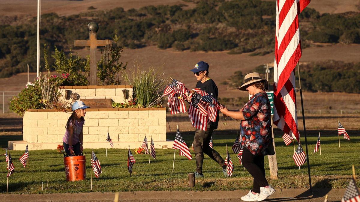 Volunteers set flags out at Los Osos Valley Mortuary and Memorial Park on Friday, Nov. 10, 2023, the day before Veterans Day. From left, Fiona Giannetto, her mother Shamarah and Alison Rupe worked to mark the graves of veterans in honor of the holiday.