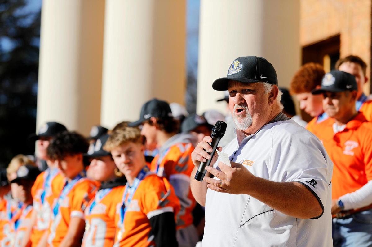 Atascadero Coach Vic Cooper salutes the state champion Greyhound football team during a parade to City Hall on Wednesday, Dec. 21, 2022.