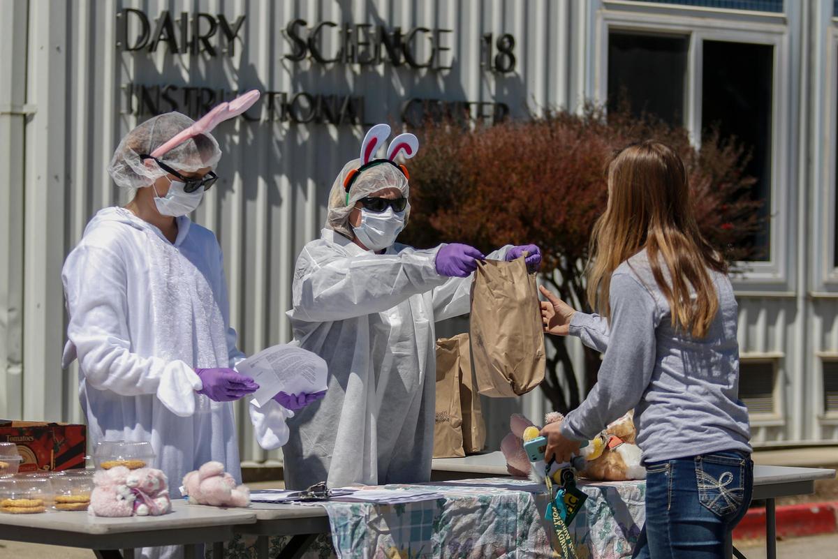 Dr. Jaymie Noland, middle, and assistant Nicole Einfalt, left, hand out lunches to Cal Poly animal science students on Friday. The lunch was a thank-you sent by alum Jake Odello for their work caring for campus animals during the COVID-19 outbreak.