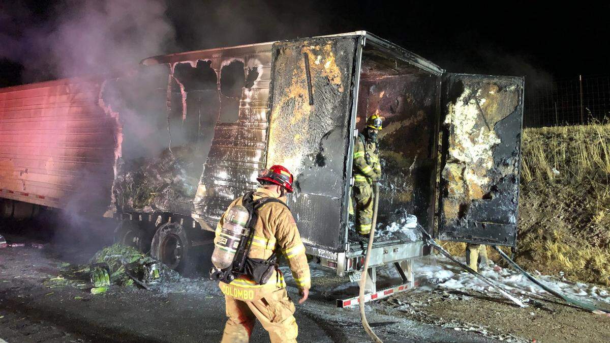 Firefighters look inside the charred remains of a semi-truck trailer filled with asparagus that caught fire on Highway 46 East in Paso Robles around 4 a.m. on July 25, 2022.