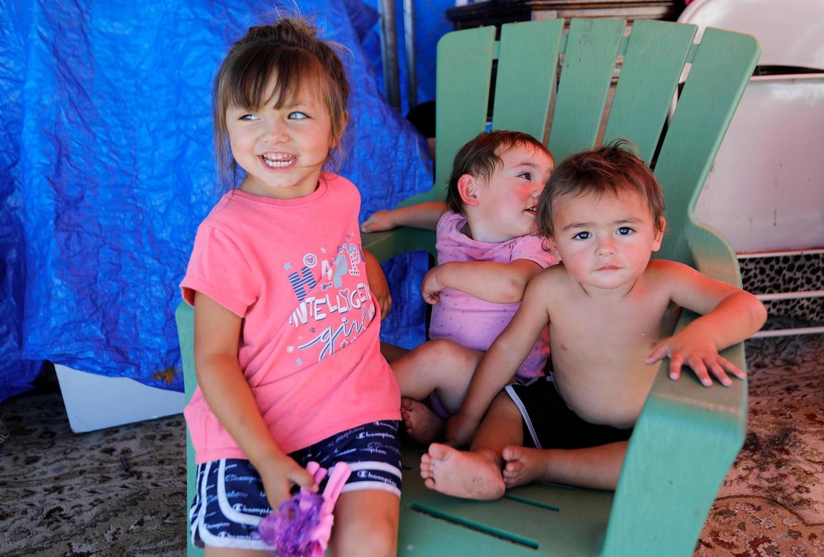 The Mejia family’s children Lorelei, 4, and twins Cain and Leila, 1, play on a chair at the Oklahoma Avenue Safe Parking Site. Mallory Mejia, a long-term site resident has been vocal about problems they see with the facility.