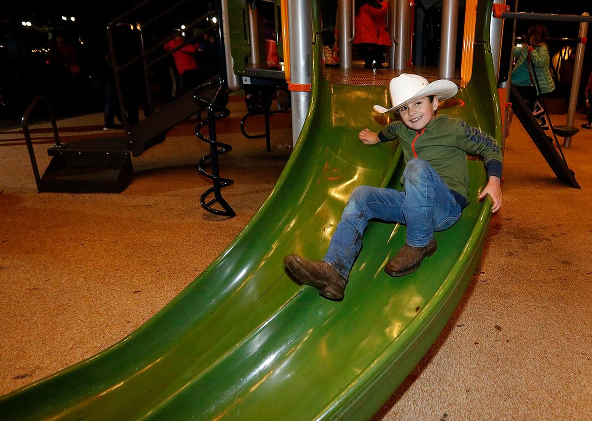 Jackson Place, 5 of Paso Robles wears a cowboy hat as he skids down the slide at the playground in Downtown City Park on Saturday, Dec. 31, 2022. Dozens of kids scrambled on the playground equipment during a New Year’s Eve party.