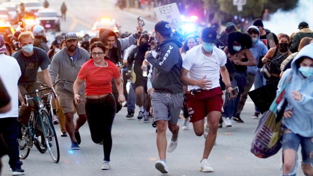 Protesters retreat Monday, June 1, 2020, as police fire tear gas after the crowd refused to leave the intersection of Santa Rosa and Walnut streets in San Luis Obispo. The altercation ended what was otherwise a peaceful march against racial injustice.