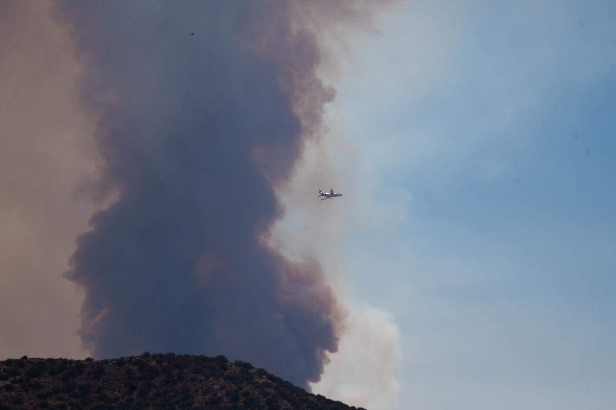 An air tanker flies past a plume of smoke as the Gifford Fire burns in eastern San Luis Obispo County on Aug. 5, 2025.