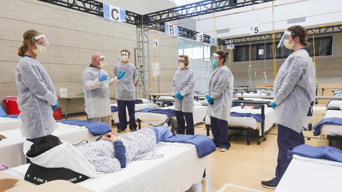 Vince Pierucci leads staff training at the Cal Poly Rec Center alternate care site, as Luydia Aguayo plays the role of patient.