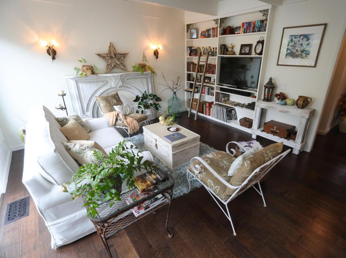 White furnishings and creamy off-white walls constrast with hand-scraped hardwood flooring in Ann Tye’s Cambria cottage.