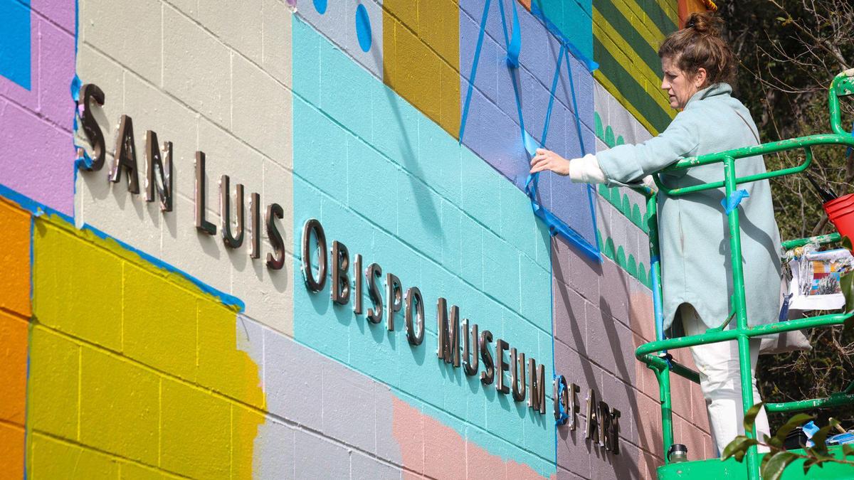 San Francisco artist Leah Rosenberg works on a new mural at the San Luis Obispo Museum of Art on Monday, Feb. 13, 2023. The mural, “SLO(W) RAINBOW,” replaces Erin LeAnn Mitchell’s “Calafia was Here,” and will be on view until February 2024. The rainbow colors are from a color palette generated from the local environment.