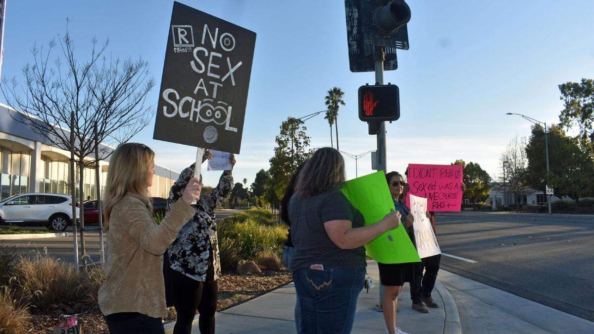 Parents and community members gather Tuesday, Feb. 8, 2022, outside the Santa Maria Joint Union High School District office and hold signs with messages such as “No sex at school” in response to alleged misconduct involving two staff members at Righetti High School in Orcutt.