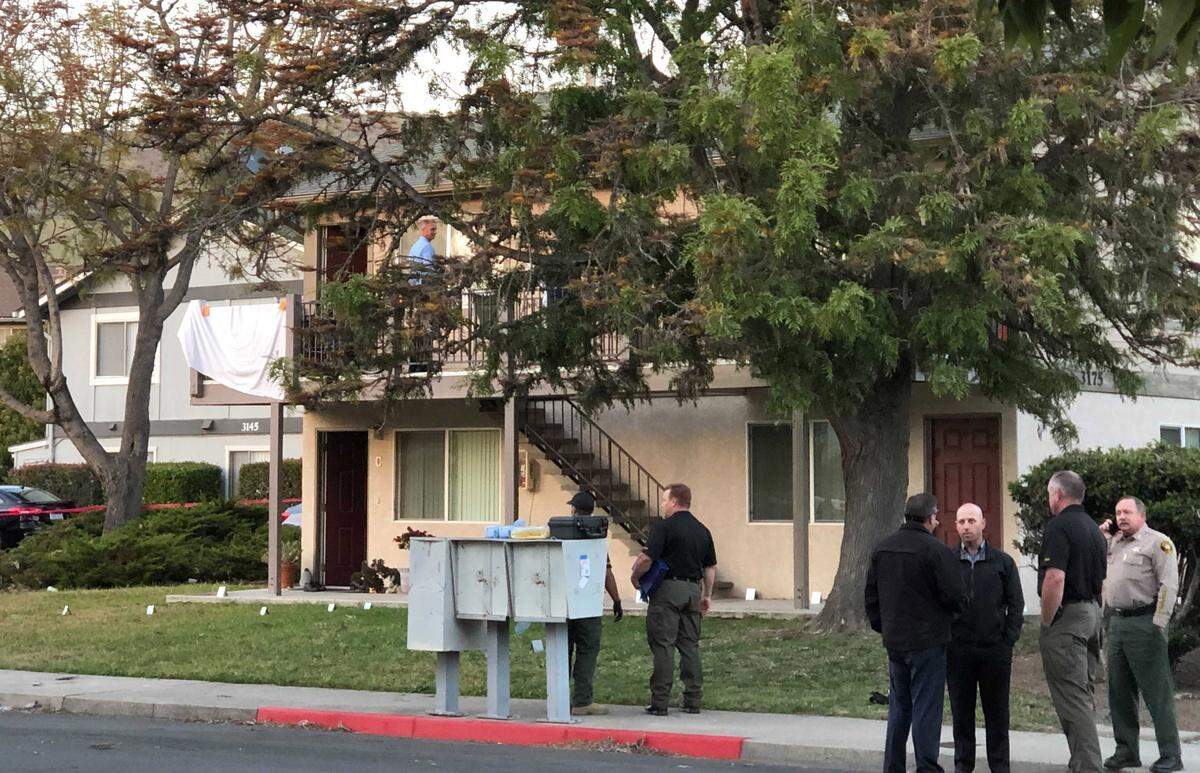 Police investigate the scene of Monday’s shooting in San Luis Obispo. Two police officers were shot and a suspect is dead. Police hung a sheet over the railing, blocking view of the doorway.