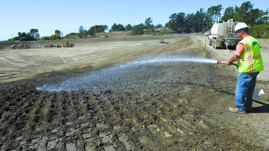 Jim Tuzzio sprays down dirt at the 3-acre evaporation pond, where brine will be discharged.