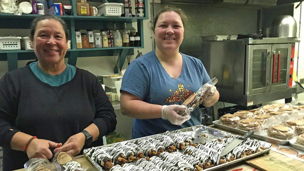 Bubbly mother-daughter baking team, from left, Monica and Tyler Nichol, pair up to individually package the fat ‘Naughty Rod’ desserts from Cambria’s popular Red Moose Cookie Company. They, along with husband/father George Nichol, are the new owners of the tiny bakery tucked into an industrial park area.