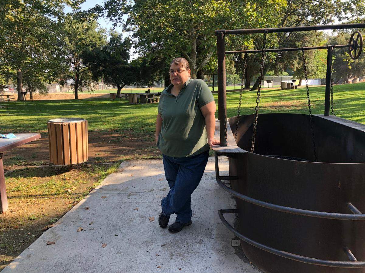 Becky Maxwell at the Atascadero Lake Park where her father helped lead a number of beautification projects, including installing picnic tables, benches and barbecue pits, like the one she is leaning against.