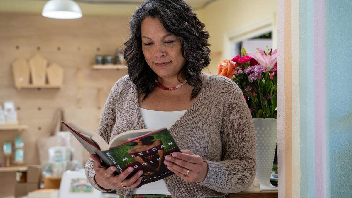 Salty Pages owner Julie Saunders reads a page of "Mexican Gothic" in her Cambria store on Wednesday, March 25, 2026. The bookstore opened on March 20 with a collection of around 300 books to start.
