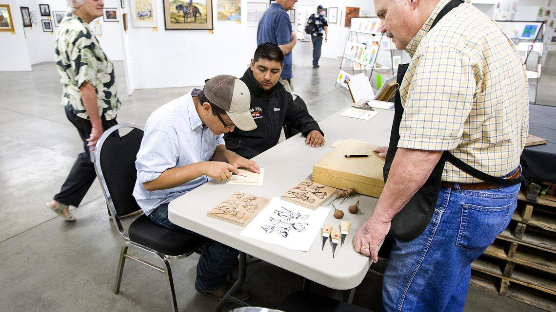 Robert Simola teaches Aaron Bernal, 16, of Santa Maria, left, and Ulises Cruz, 17, of Nipomo how to carve wood for making woodblock prints at the California Mid-State Fair on Tuesday morning.