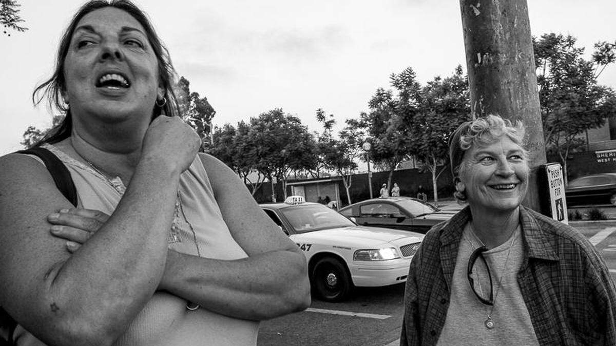 Mary Lucey (left) and Nacy MacNeil (right) stand at a memorial vigil for former ACT UP Los Angeles and Chicago member Ferd Eggan. Lucey and MacNeil died Feb. 11, 2023, in Oceano.
